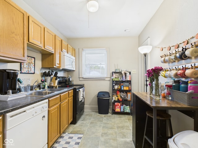 kitchen with white appliances, dark countertops, and a sink