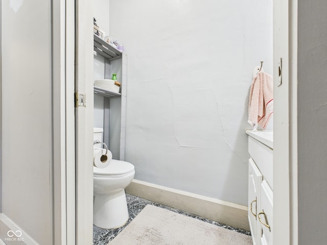 bathroom featuring toilet, baseboards, and vanity