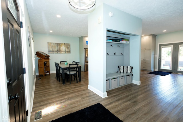 foyer entrance with visible vents, baseboards, a textured ceiling, and wood finished floors