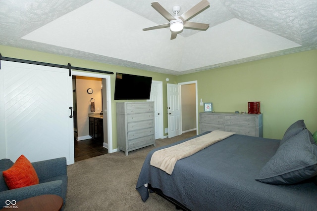 bedroom with carpet flooring, a textured ceiling, a barn door, and connected bathroom