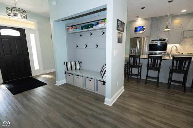 mudroom with recessed lighting, baseboards, dark wood finished floors, and a sink