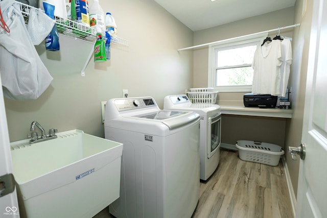laundry room with independent washer and dryer, laundry area, a sink, and light wood-type flooring