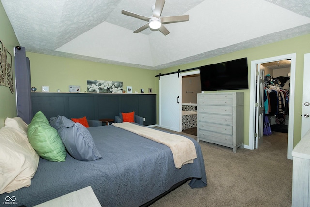 bedroom featuring carpet flooring, a barn door, a walk in closet, a ceiling fan, and a closet