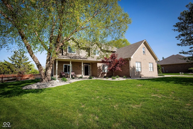 traditional home featuring brick siding, fence, and a front yard