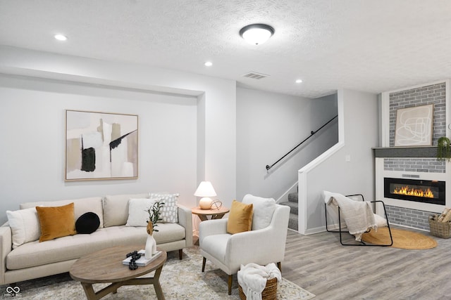 1417 E Michigan St, Indianapolis, IN 46201 - living area featuring a textured ceiling, visible vents, a fireplace, wood finished floors, and stairway