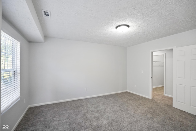 1417 E Michigan St, Indianapolis, IN 46201 - interior space featuring a walk in closet, a textured ceiling, baseboards, a closet, and carpet