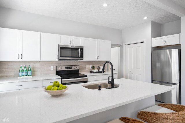 1417 E Michigan St, Indianapolis, IN 46201 - kitchen with white cabinets, appliances with stainless steel finishes, light stone counters, a sink, and decorative backsplash