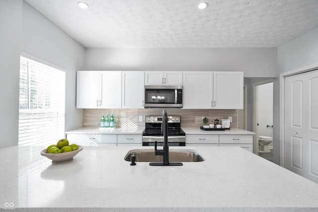 1417 E Michigan St, Indianapolis, IN 46201 - kitchen with light stone counters, decorative backsplash, stainless steel appliances, and white cabinetry
