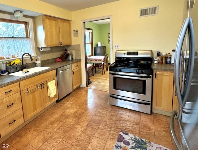 2405 Sycamore St, Columbus, IN 47201 - kitchen with stainless steel appliances, a sink, dark countertops, light brown cabinets, and backsplash