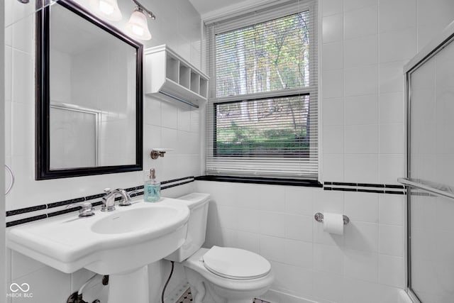 bathroom with a healthy amount of sunlight, tile walls, and toilet