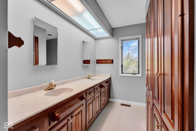 bathroom featuring a sink, baseboards, double vanity, and visible vents