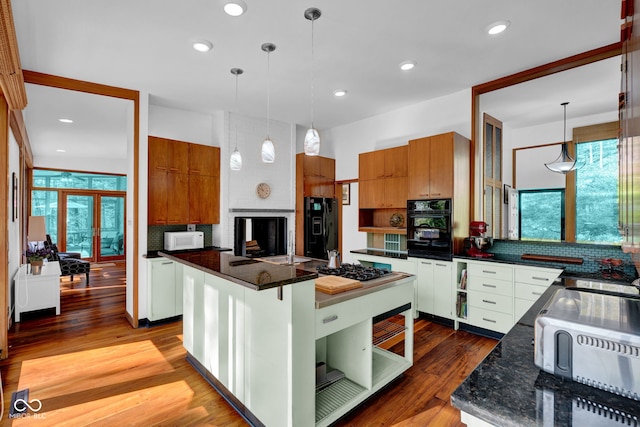 kitchen with backsplash, brown cabinets, wood finished floors, and black appliances