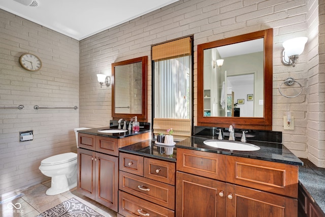 full bath with a sink, toilet, and brick wall