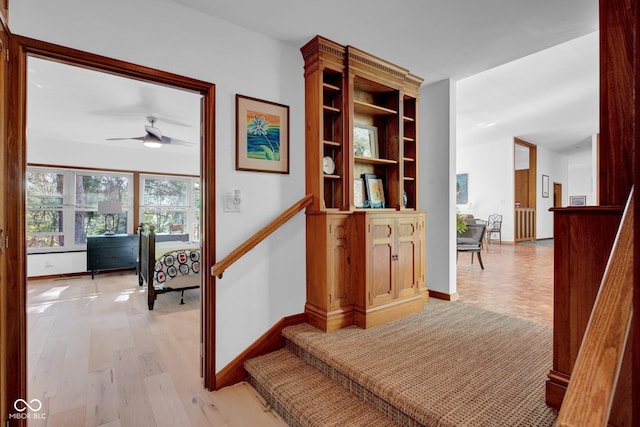 hallway featuring baseboards, stairway, and light wood-type flooring