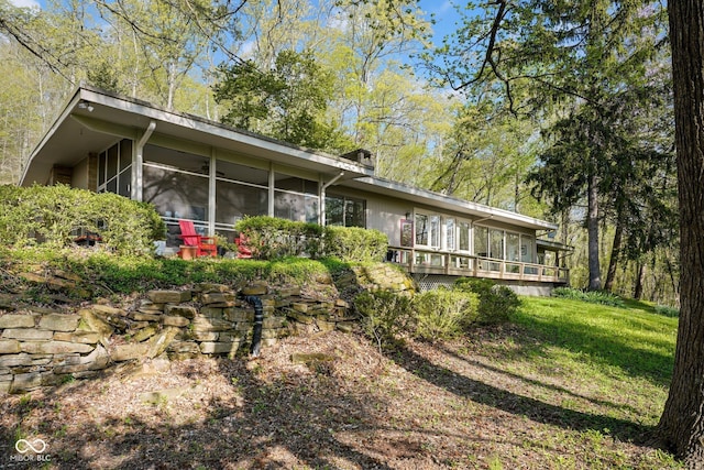 rear view of house with a sunroom and a lawn