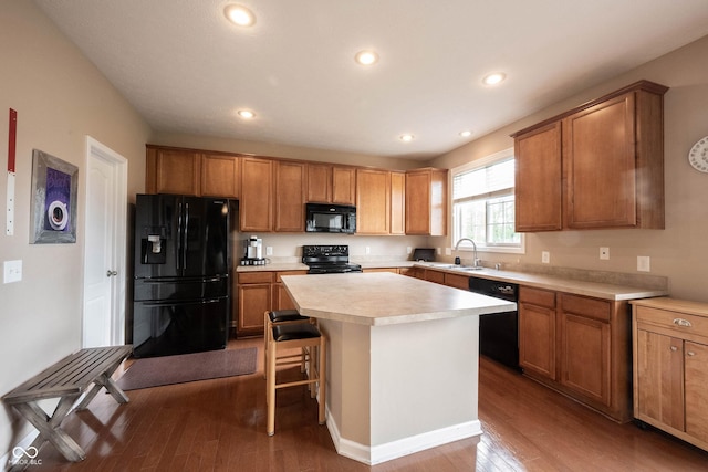 kitchen featuring a sink, wood finished floors, black appliances, and light countertops