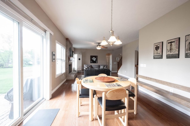 dining space with baseboards, light wood-style floors, and ceiling fan with notable chandelier
