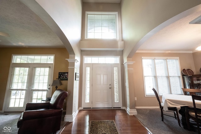 foyer entrance with ornate columns, arched walkways, baseboards, and a healthy amount of sunlight