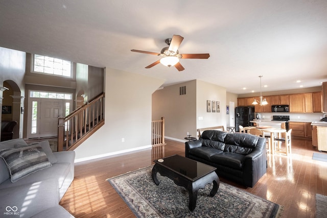 living room with arched walkways, baseboards, light wood finished floors, and visible vents