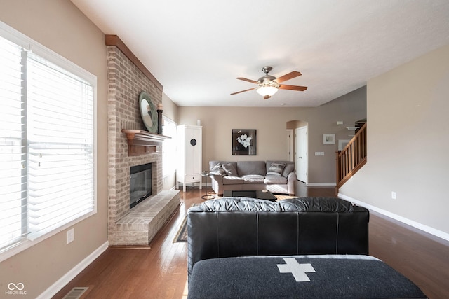 living area featuring baseboards, a ceiling fan, wood finished floors, and a fireplace