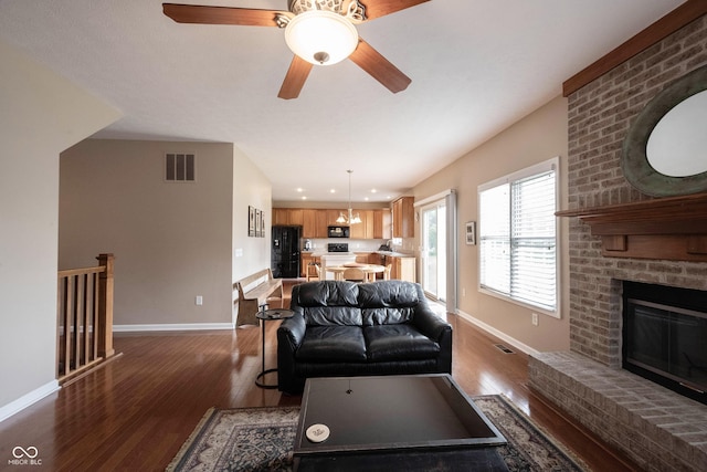 living room featuring a fireplace, baseboards, visible vents, and dark wood-type flooring