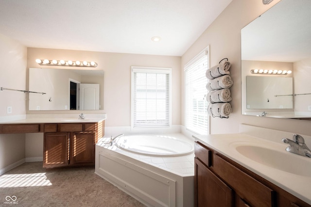 bathroom featuring a sink, a garden tub, and two vanities