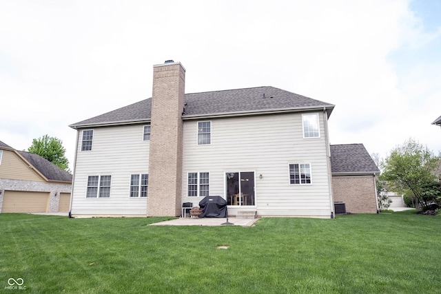 back of house with central AC unit, a patio area, a yard, and a chimney