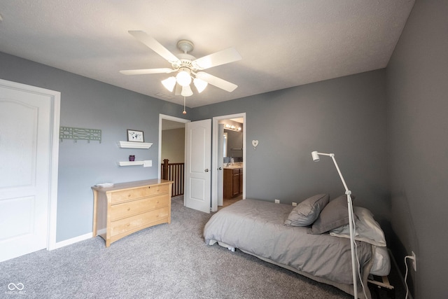 bedroom featuring ceiling fan, light carpet, baseboards, and ensuite bath
