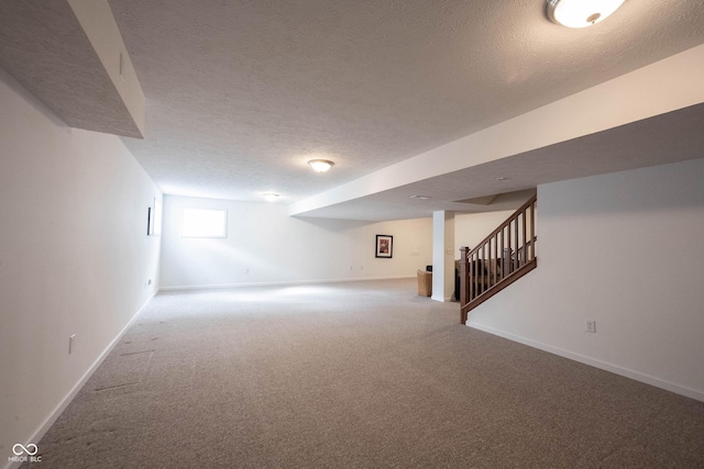 below grade area with baseboards, carpet, stairs, and a textured ceiling