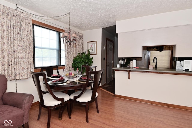 114 E 27th St, Indianapolis, IN 46205 - dining room featuring wood finished floors, a textured ceiling, a chandelier, and baseboards