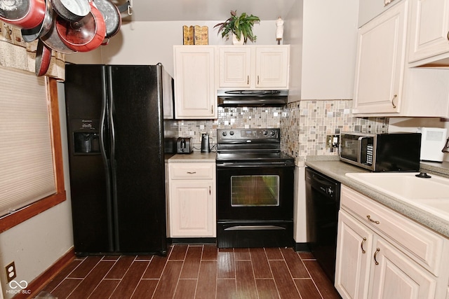 114 E 27th St, Indianapolis, IN 46205 - kitchen with black appliances, under cabinet range hood, dark wood finished floors, and tasteful backsplash