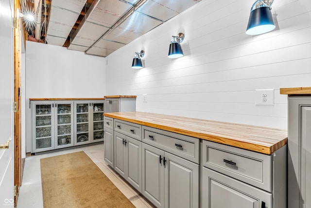 interior space featuring wooden walls, wooden counters, and gray cabinets