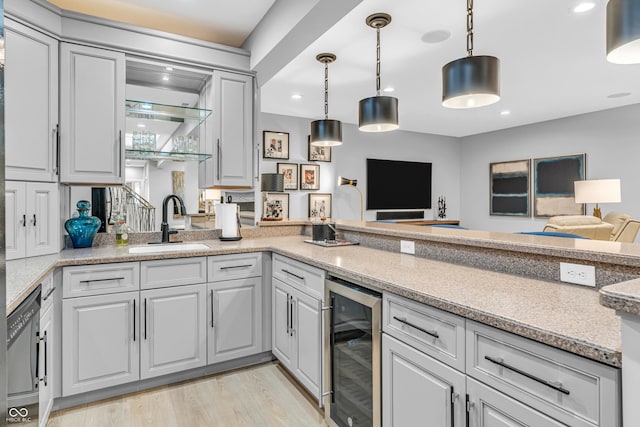 kitchen featuring a sink, beverage cooler, recessed lighting, decorative light fixtures, and light wood-type flooring