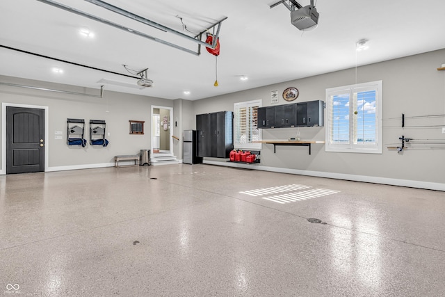 garage featuring baseboards, freestanding refrigerator, and a garage door opener
