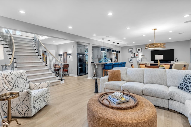 living room with recessed lighting, baseboards, stairway, and light wood-style floors
