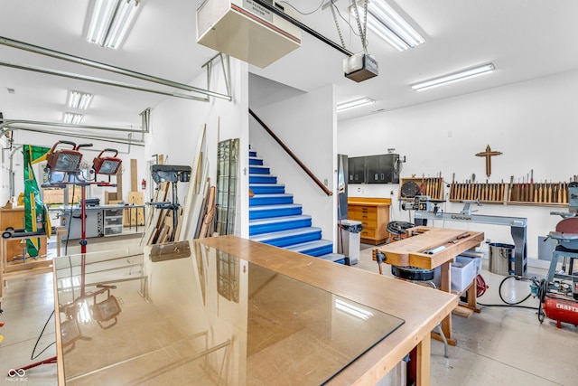 garage with a garage door opener, freestanding refrigerator, and a workshop area