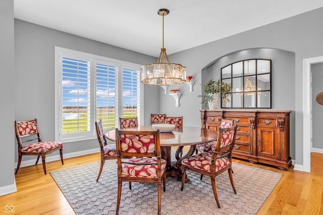 dining area featuring baseboards, light wood-type flooring, and a notable chandelier