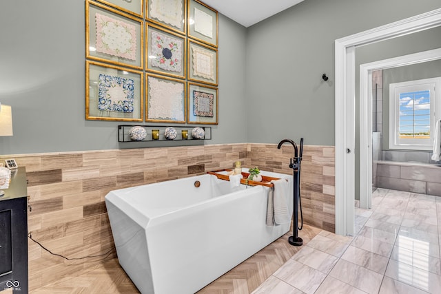 bathroom featuring a freestanding tub, tile walls, and a wainscoted wall