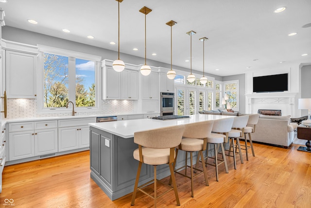 kitchen featuring visible vents, a kitchen bar, a center island, light countertops, and backsplash