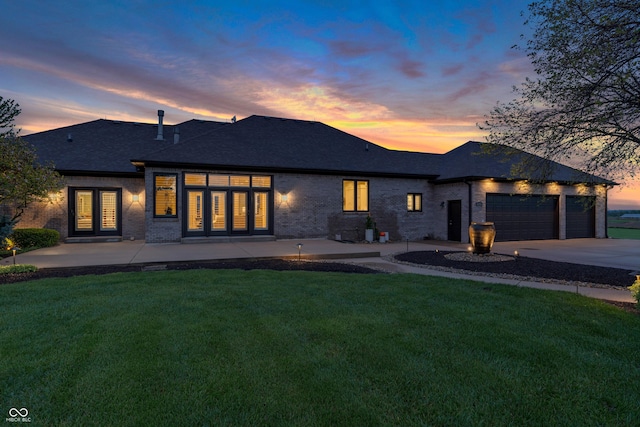view of front of home featuring brick siding, a garage, driveway, and a front yard