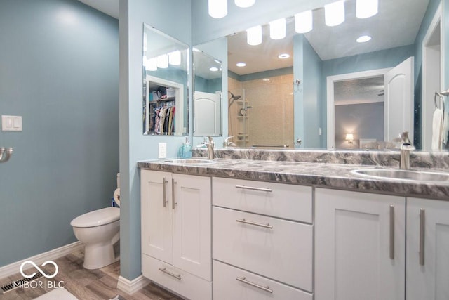 full bath featuring a sink, wood finished floors, toilet, and a shower stall