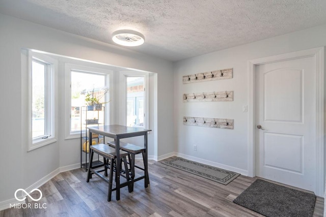 dining area featuring baseboards, a textured ceiling, and wood finished floors