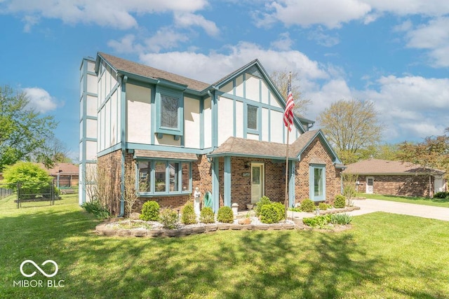tudor house featuring brick siding, fence, stucco siding, and a front yard