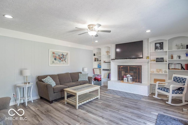 living room with a textured ceiling, ceiling fan, and wood finished floors