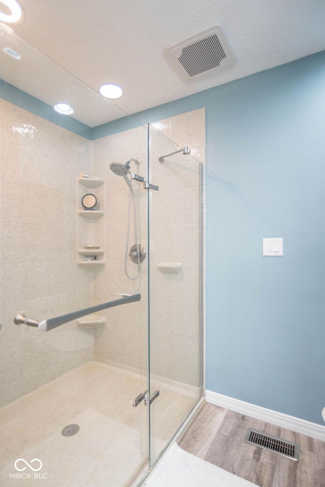 full bath featuring baseboards, visible vents, wood finished floors, and a stall shower