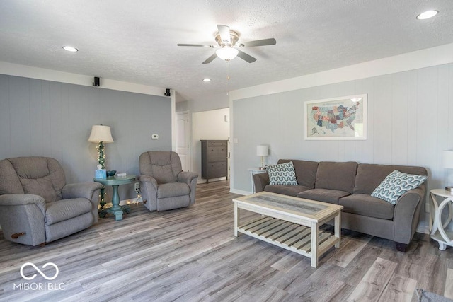 living area with light wood-style floors, a ceiling fan, recessed lighting, and a textured ceiling
