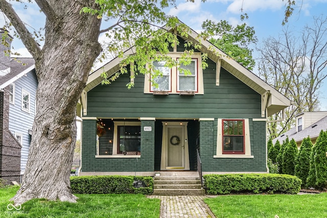 view of front of house with brick siding, a front lawn, and entry steps