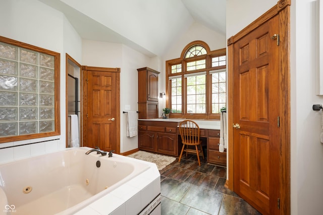 full bath featuring a jetted tub, vaulted ceiling, and vanity