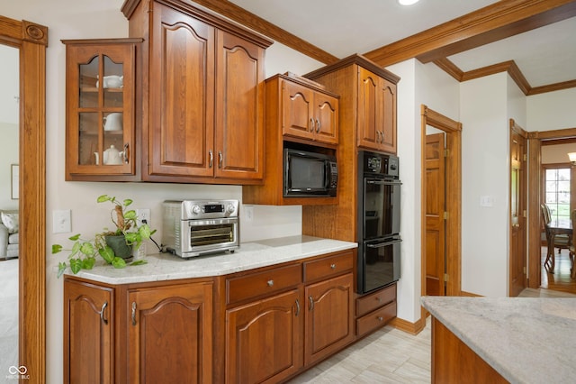 kitchen featuring brown cabinets, a toaster, light stone counters, black appliances, and glass insert cabinets