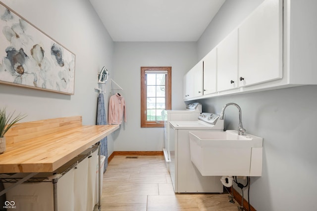 laundry room featuring cabinet space, baseboards, a sink, and washer and clothes dryer